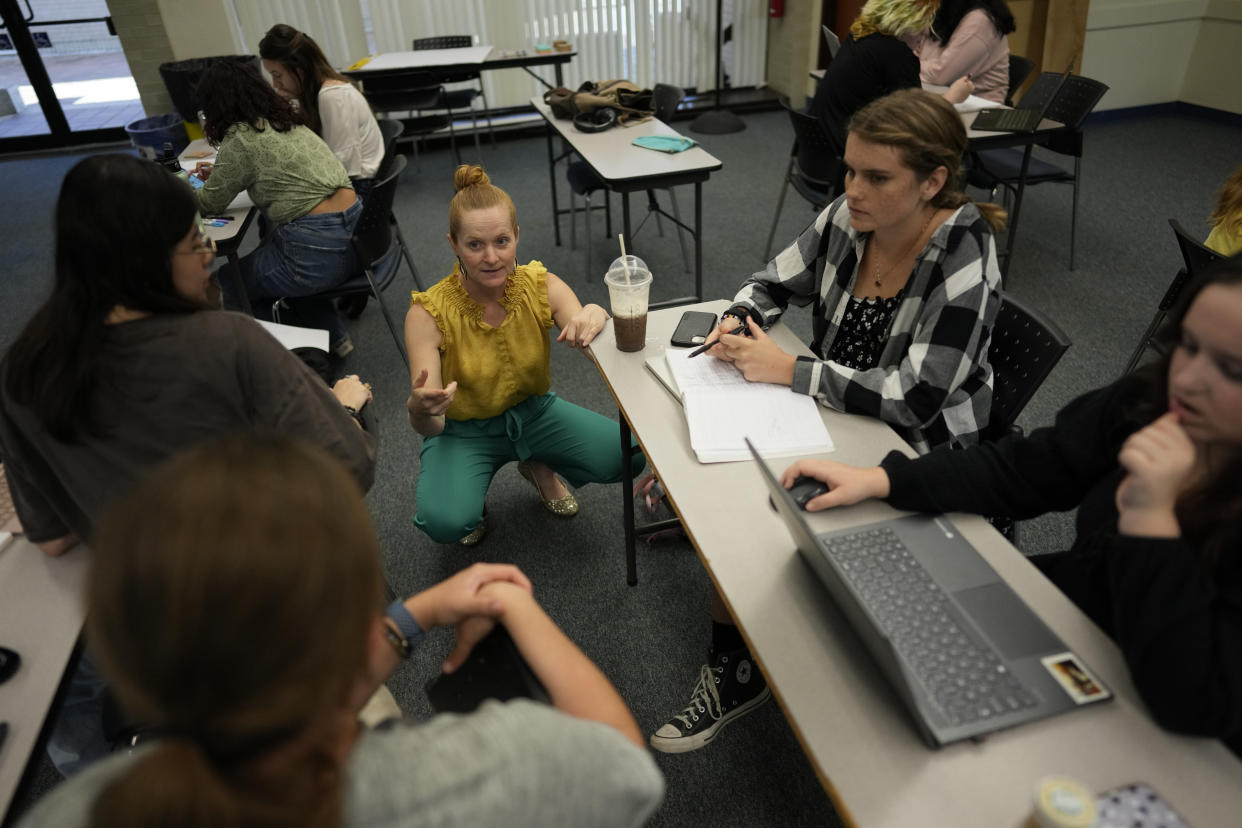 Jennifer Wells, center, director of writing at New College of Florida, checks in with students working on an in-class project, during her "Rhetoric of Walt Disney World" class, Thursday, March 2, 2023, in Sarasota, Fla. Wells says the school's small class sizes allow her to focus on student needs and get to know everyone in her classes, while the flexibility that students get to choose their classes and majors is unique, especially for a public liberal arts college. (AP Photo/Rebecca Blackwell)