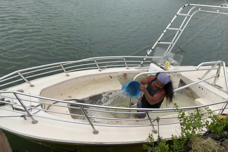 Arnold Balbin bails out water from a commercial parasailing boat moored at the Gregorio D. Perez Marina in Hagatna, Guam, Thursday, May 25, 2023, after Typhoon Mawar went through the area. (AP Photo/Grace Garces Bordallo)