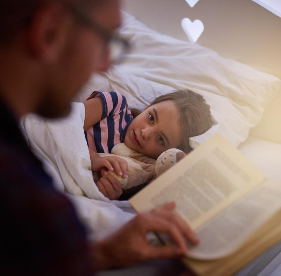 Shot of a father reading a bedtime story to his daughter