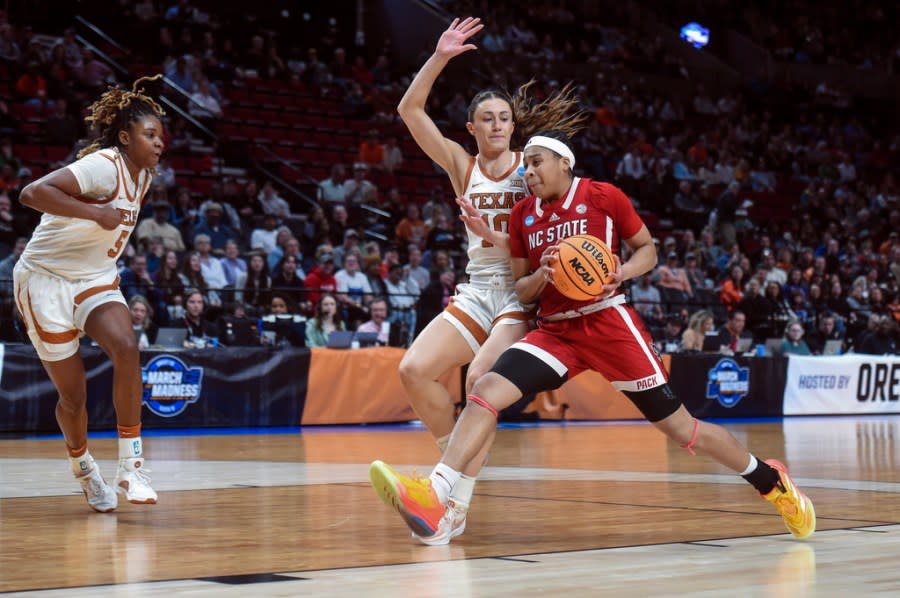 North Carolina State guard Zoe Brooks, right, drives to the basket as Texas guard Shay Holle (10) defends during the first half of an Elite Eight college basketball game in the women’s NCAA Tournament, Sunday, March 31, 2024, in Portland, Ore. (AP Photo/Steve Dykes)