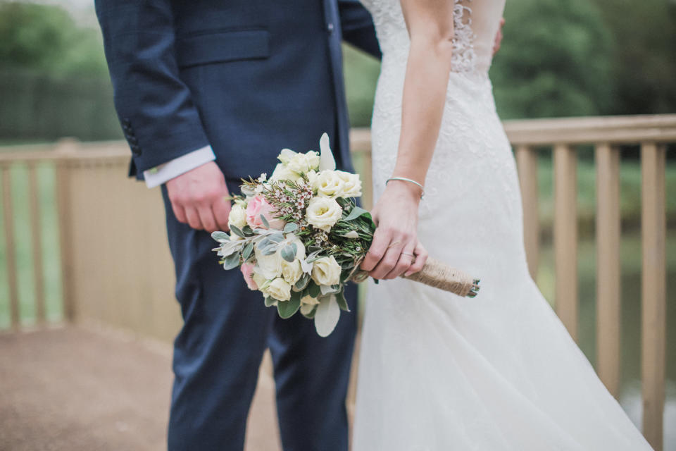 A bride holding her bouquet of flowers and a groom on their wedding day