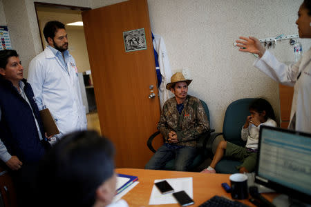 Honduran migrant Alvin Reyes, 39, talks with doctors about the condition of his wife Erly Marcial, 21, who is eight months pregnant, at a hospital in Puebla, Mexico, November 12, 2018. REUTERS/Carlos Garcia Rawlins