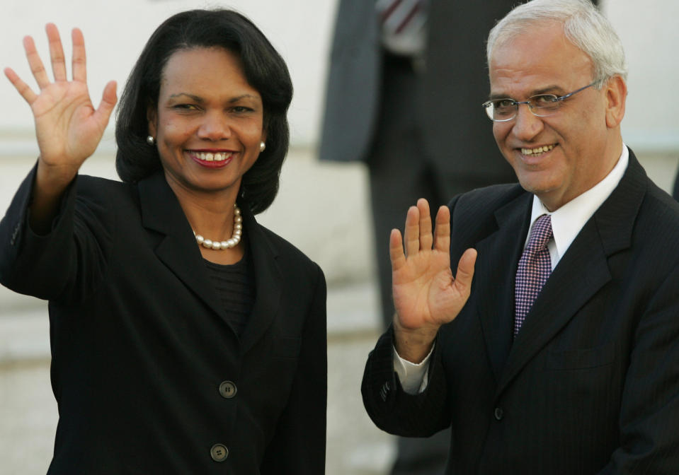 FILE- In this Oct. 4, 2006 file photo, then U.S. Secretary of State Condoleezza Rice, left, and Palestinian chief negotiator Saeb Erekat, wave as Rice arrives to Palestinian President Mahmoud Abbas' office in the West Bank city of Ramallah. Erekat, a veteran peace negotiator and prominent international spokesman for the Palestinians for more than three decades, died Tuesday, Nov. 10, 2020. He was 65. (AP Photo/Kevin Frayer, File)