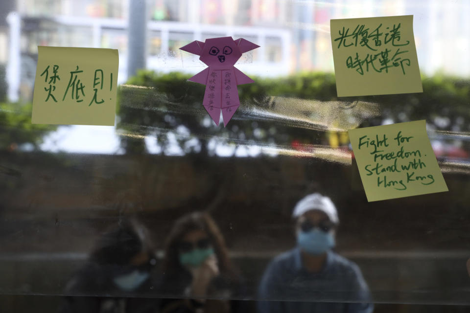 People sit near notes on a Lennon wall during a rally for students and elderly pro-democracy demonstrators in Hong Kong, Saturday, Nov. 30, 2019. Hundreds of Hong Kong pro-democracy activists rallied Friday outside the British Consulate, urging the city's former colonial ruler to emulate the U.S. and take concrete actions to support their cause, as police ended a blockade of a university campus after 12 days. (AP Photo/Ng Han Guan)