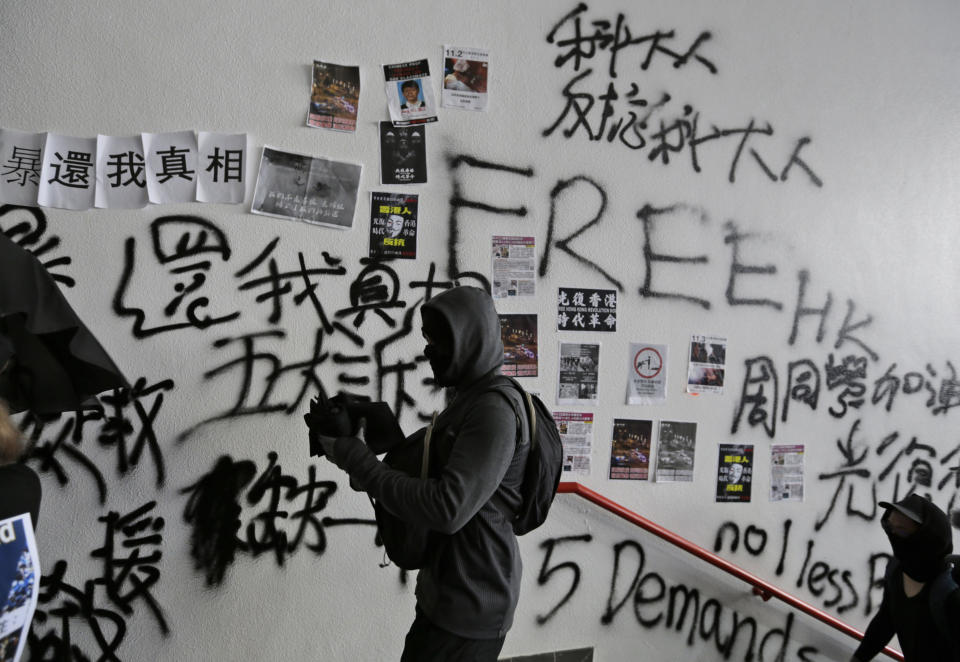 A protester walks past a vandalized wall during an anti-government rally at Hong Kong University of Science and Technology in Hong Kong, Thursday, Nov. 7, 2019. (AP Photo/Dita Alangkara)