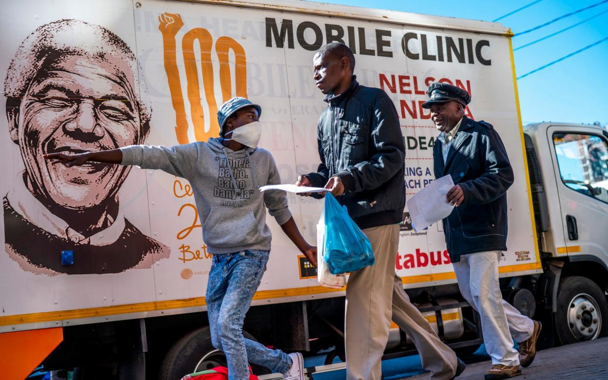 A volunteer directs two men towards a medical tent where they will be tested for Covid-19 as well as HIV and Tuberculosis, in downtown Johannesburg in April - AP