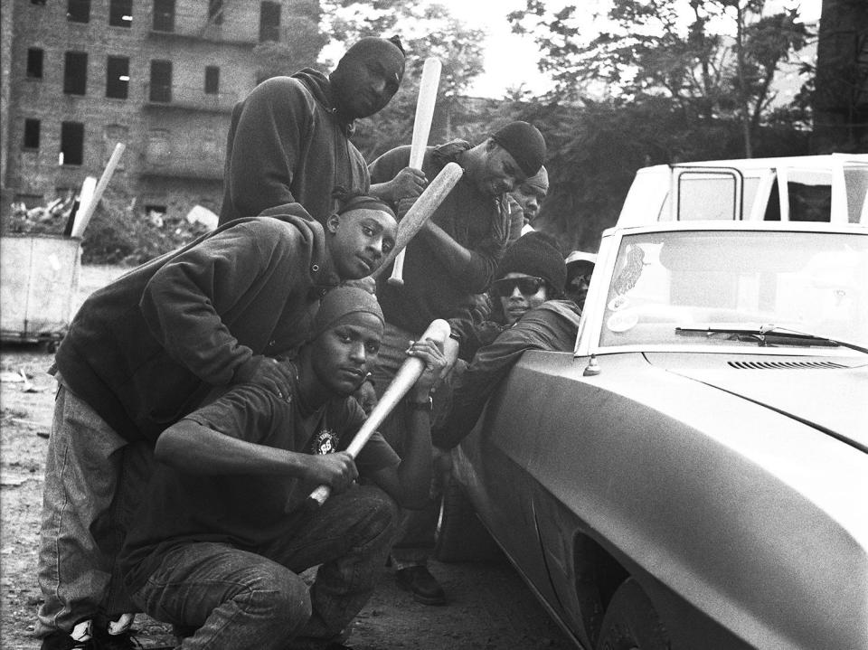 Kevin Bray dressed as Eazy E in a car surrounded by men with bats.