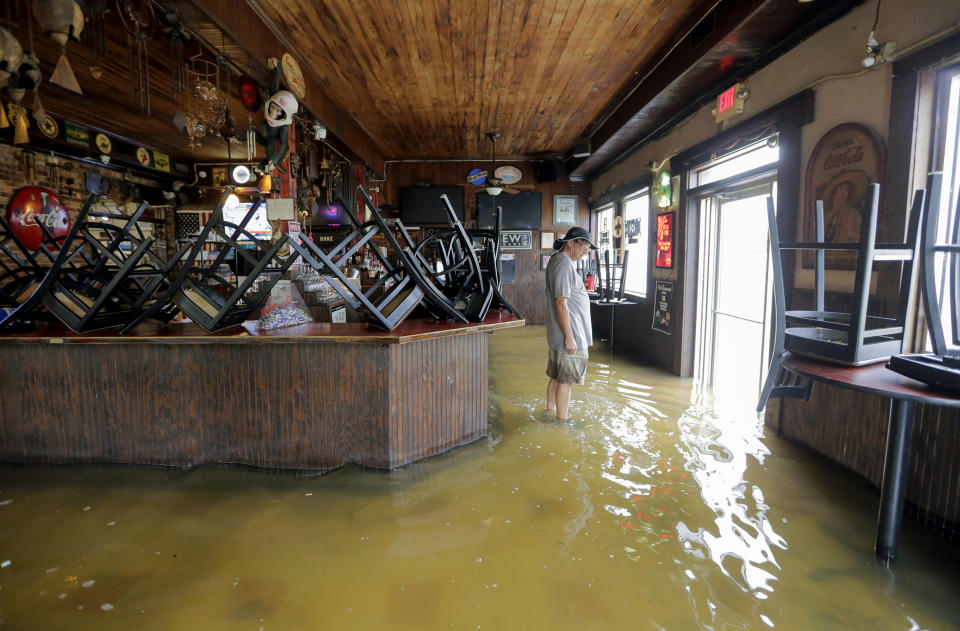 A man stands in floodwaters at Don'z On the Lake as Tropical Storm Barry's winds push water over the Lake Pontchartrain seawall Saturday, July 13, 2019. (David Grunfeld/The Advocate via AP)