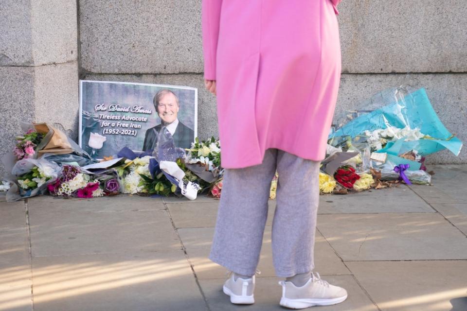 A person views flowers left in memory of Sir David Amess outside the Houses of Parliament (Dominic Lipinski/PA) (PA Wire)