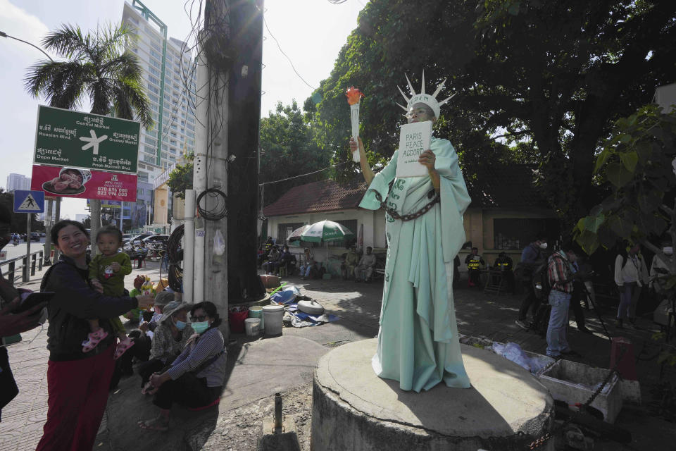 Cambodian-American lawyer Theary Seng, dressed in the Lady Liberty, stands outside the Phnom Penh Municipal Court in Phnom Penh, Cambodia, Tuesday, June 14, 2022. The Cambodian American lawyer and dozens of members of a now-dissolved opposition party were convicted of treason Tuesday in a trial that was the latest move to tame all opposition to the long-running rule of Prime Minister Hun Sen. (AP Photo/Heng Sinith)