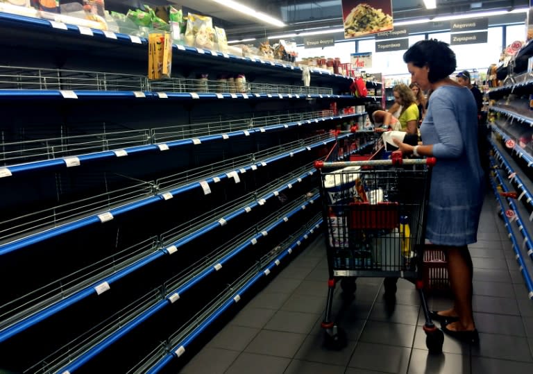 Shoppers stand in an aisle with empty shelves in a supermarket in Athens on July 4, 2015