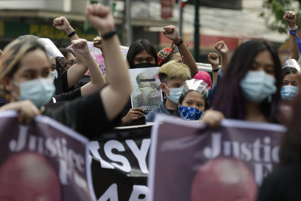 Protesters raise their clenched fists during a rally outside Manila's North Cemetery, Philippines where detained left-wing activist Reina Mae Nasino attends funeral rites of her three-month-old firstborn named River on Friday Oct. 16, 2020. Left-wing groups on Friday decried as brutal the treatment of a detained activist, who was allowed by a Manila court to attend her baby's burial but was restrained with handcuffs, a sweltering protective suit and swarms of armed escorts as she quietly wept. (AP Photo/Aaron Favila)