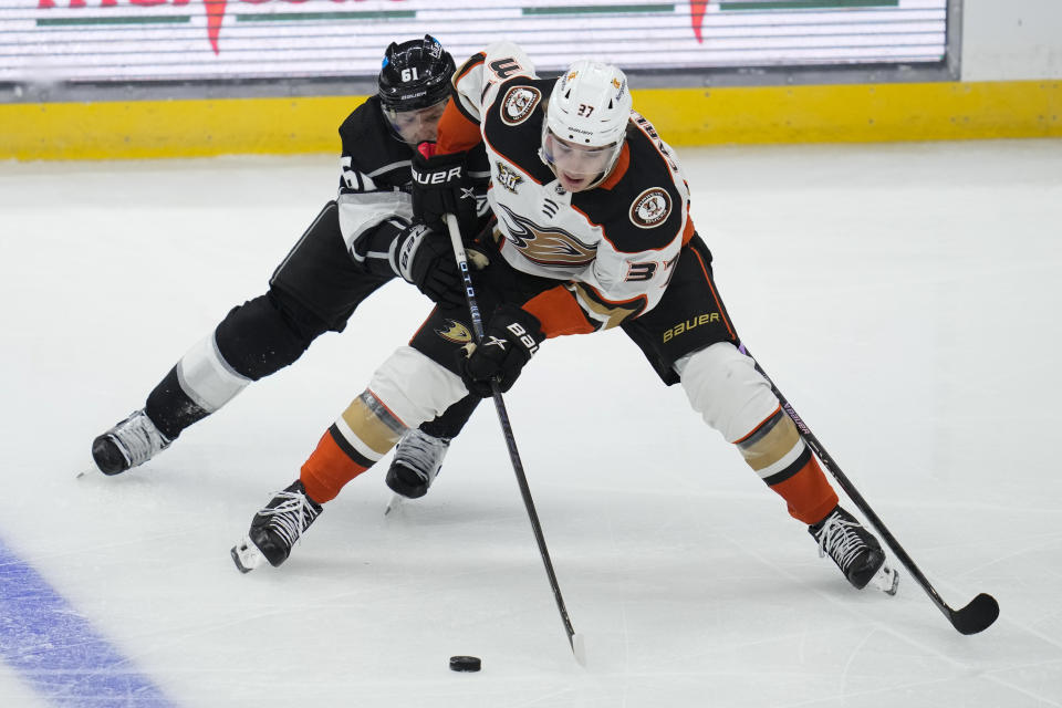 Anaheim Ducks center Leo Carlsson (37) controls the puck against Los Angeles Kings Trevor Lewis (61) during the third period of a preseason NHL hockey game Tuesday, Oct. 3, 2023, in Los Angeles. (AP Photo/Ashley Landis)