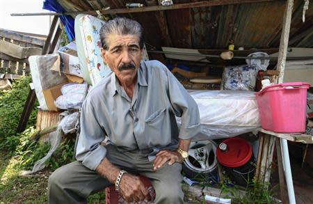 Mattress repairman and fruit vendor Angelo Lopez poses outside the shed which he calls his factory in Lares, western Puerto Rico, April 7, 2014. REUTERS/Ana Martinez