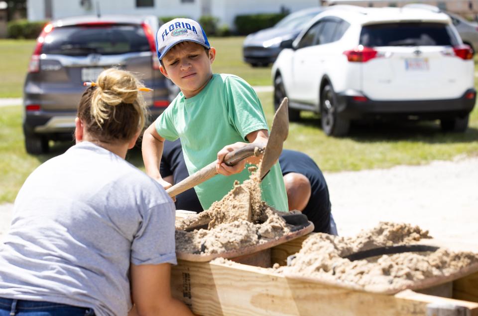 Carson Storm, 12, helps his mother, Kaitlin, fill bags with sand Monday at the Belleview Sportsplex as people prepared for Tropical Storm Idalia.