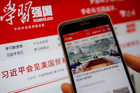 Chinese government propaganda app Xuexi Qiangguo, which literally translates as 'Study to make China strong', is seen on a mobile phone in front of its website on a computer screen in this illustration picture taken February 18, 2019. REUTERS/Tingshu Wang/Illustration