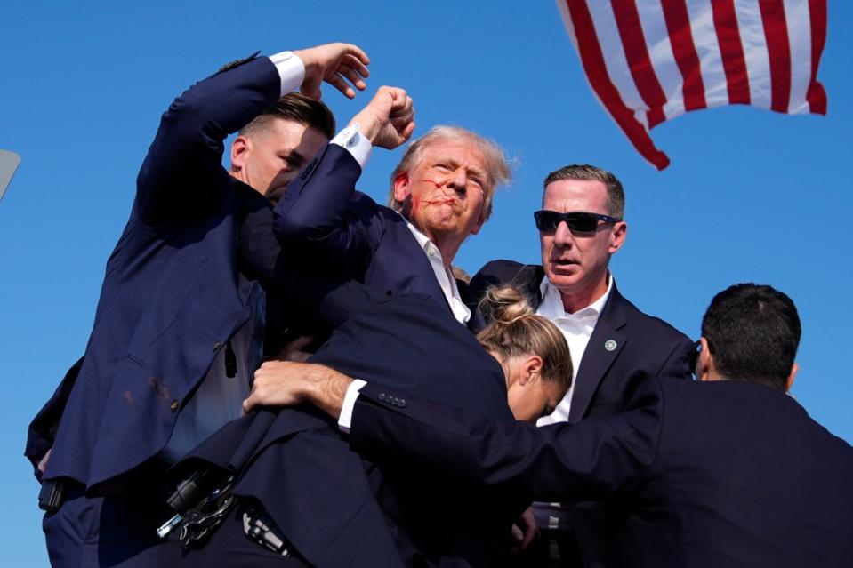 Trump raises his fist after the shooting. AP