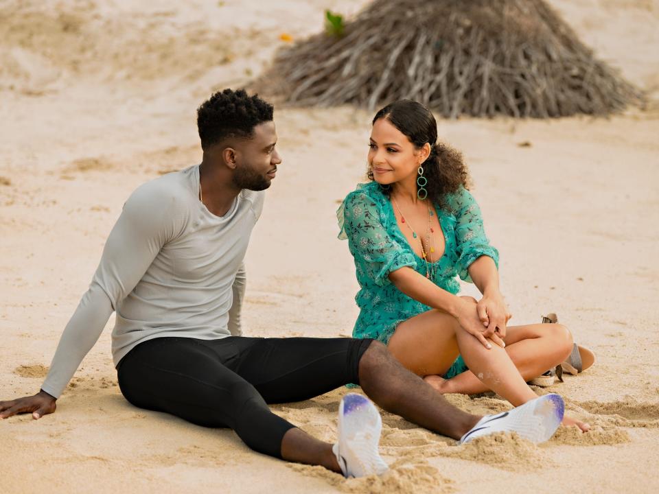 main characters sitting on beach in resort to love