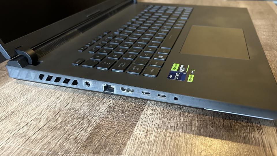 Asus ROG Strix Scar 18 side showing transparent plastic and ports on a wooden table