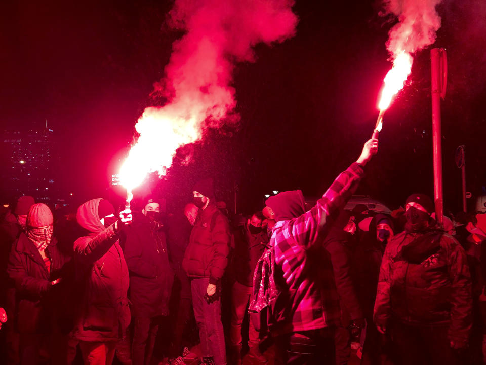 People light flares as they march near the ruling Law and Justice party headquarters in Warsaw, Poland Wednesday Jan. 27, 2021 to protest after the country's top court on Wednesday confirmed its highly divisive ruling that will further tighten the predominantly Catholic nation's strict anti-abortion law. The Constitutional Tribunal published the justification of its decision, which means it can now be officially printed and take immediate effect. (AP Photo/Czarek Sokolowski)