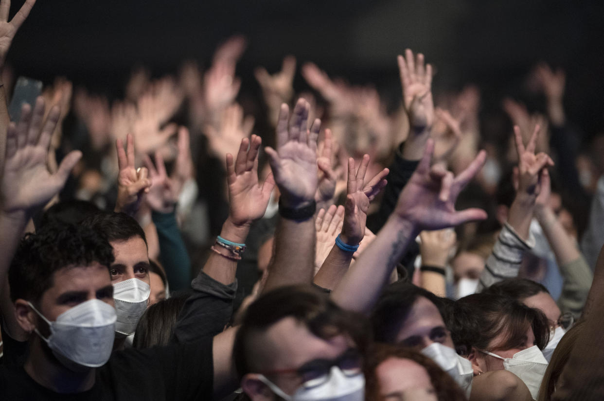 People attend a music concert in Barcelona, Spain, Saturday, March 27, 2021. Five thousand music lovers are set to attend a rock concert in Barcelona on Saturday after passing a same-day COVID-19 screening to test its effectiveness in preventing outbreaks of the virus at large cultural events. The show by Spanish rock group Love of Lesbian has the special permission of Spanish health authorities. While the rest of the country is limited to gatherings of no more than four people in closed spaces, the concertgoers will be able to mix freely while wearing face masks. (AP Photo/Emilio Morenatti)