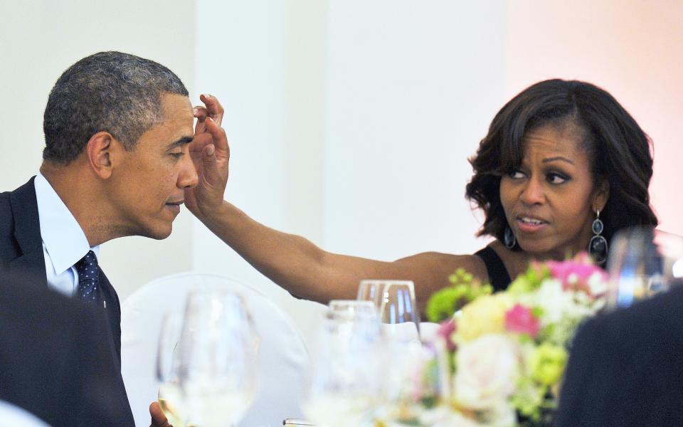 First lady Michelle Obama wipes something from President Obama's forehead during a dinner at the Schloss Charlottenburg Palace in Berlin, Germany on June 19, 2013.