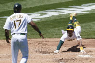 Oakland Athletics' Elvis Andrus (17) watches as Tony Kemp slides home as both scored on a two-run double hit by Matt Chapman during the second inning of a baseball game against the Kansas City Royals in Oakland, Calif., Saturday, June 12, 2021. (AP Photo/Jeff Chiu)