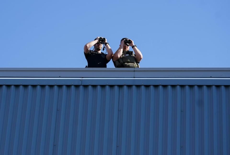 RCMP security detail use binoculars to watch protesters as Liberal Leader Justin Trudeau makes a campaign stop at a steel plant during the Canadian federal election campaign in Welland, Ont., Monday, Sept. 6, 2021.