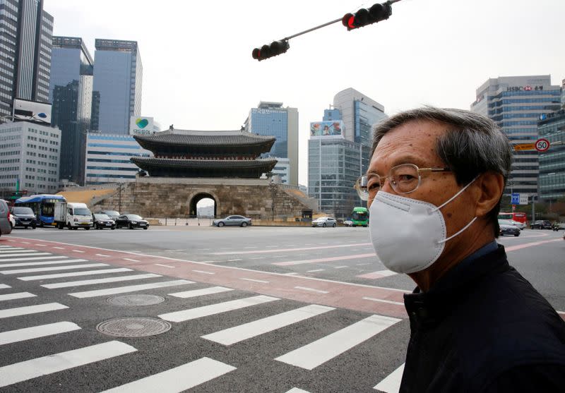 A man wearing a mask as a preventive measure against the coronavirus waits for a signal at a zebra crossing in downtown Seoul