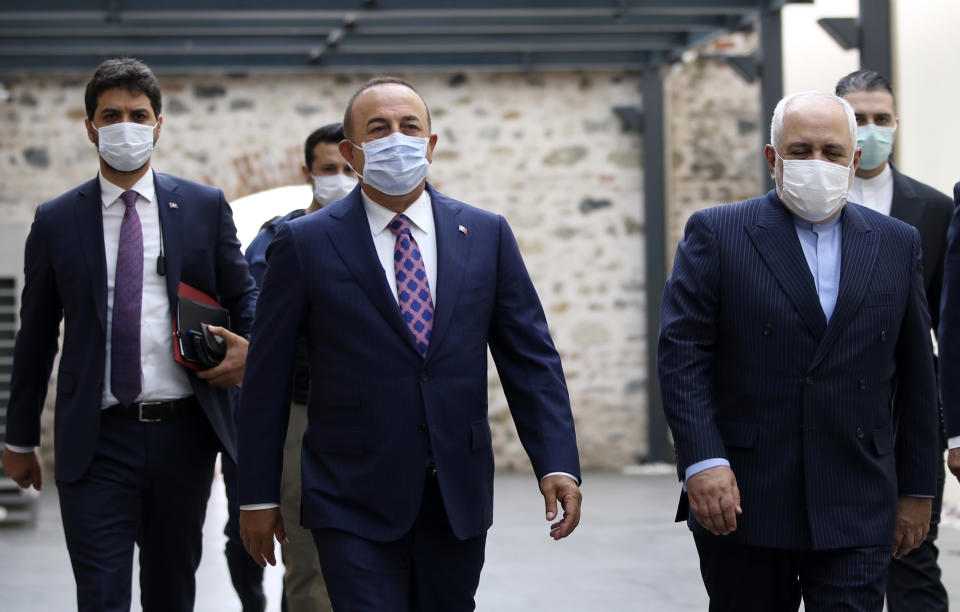 Turkish Foreign Minister Mevlut Cavusoglu, center, and Iran's Foreign Minister Mohammad Javad Zarif, right, wearing face masks to protect against the coronavirus, arrive for a meeting, in Istanbul, Monday, June 15, 2020. The two will discuss bilateral issues and Syria. (Turkish Foreign Ministry via AP, Pool)