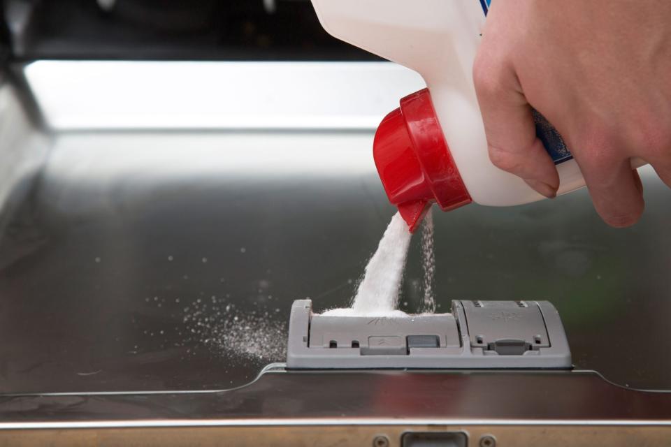 Pouring dish detergent powder into dishwasher