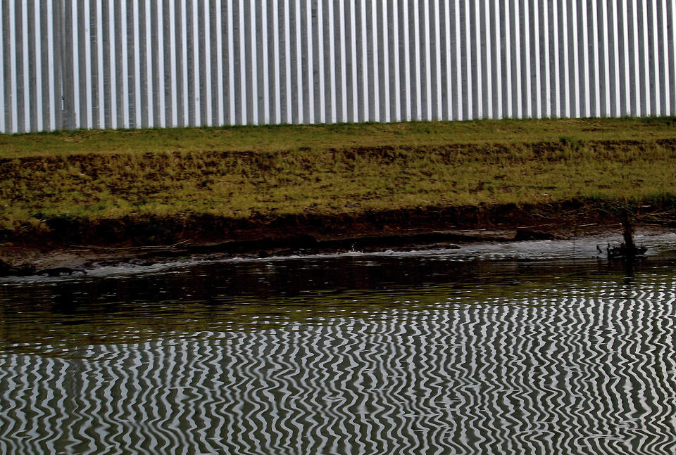 FILE - In this Monday, April 5, 2021, file photo, the reflection of a private border wall is seen on the glassy waters of the Rio Grande on Monday, April 5, 2021, in Mission, Texas. The Biden administration said Friday it will begin work to address risks of flooding and soil erosion from the unfinished wall on the U.S. border with Mexico and provided some answers on how it will use unspent money from shutting down one of President Donald Trump's signature domestic projects. Construction under the Trump administration "blew large holes" into the flood barrier system of low-lying regions in Texas' Rio Grande Valley, the Homeland Security Department said. It said it will "quickly repair" the flood barrier system without extending the wall. Hidalgo County, Texas, officials have expressed alarm about flooding risks during the hurricane season starting in June from breaches in a levee system after Biden halted border wall construction immediately after taking office in January. (Delcia Lopez/The Monitor via AP, File)