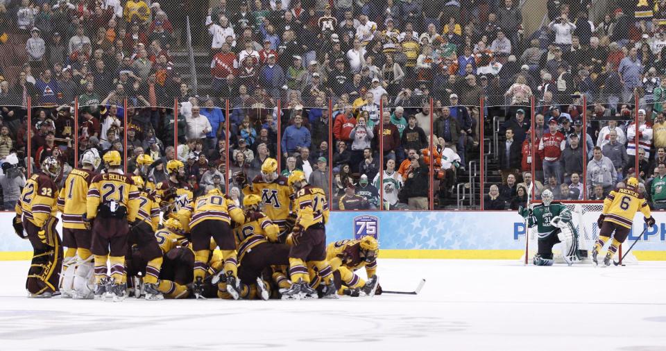 Minnesota gather around Justin Holl, who just scored the goal as Jake Parenteau (6) swings by North Dakota's Zane Gothberg during the third period of an NCAA men's college hockey Frozen Four tournament game on Thursday, April 10, 2014, in Philadelphia. Minnesota won 2-1. (AP Photo/Chris Szagola)