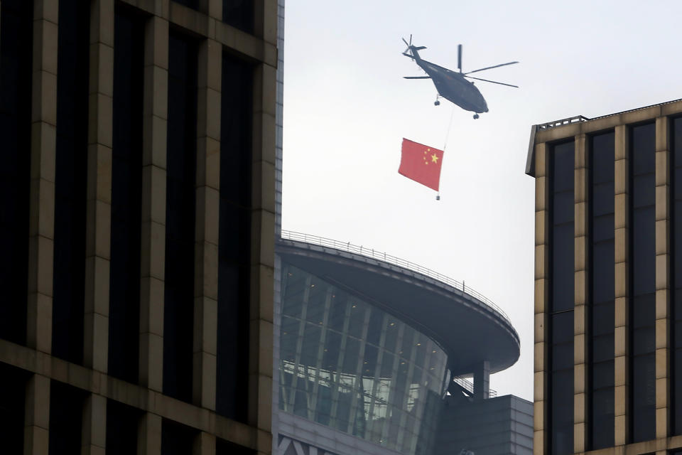 A helicopter carrying the Chinese flag flies above the central business district in Beijing, Sunday, Sept. 15, 2019. Many of the streets in the central part of China's capital were shut down this weekend for a rehearsal for what is expected to be a large military parade on Oct. 1 to commemorate the 70th anniversary of Communist China. (AP Photo/Mark Schiefelbein)