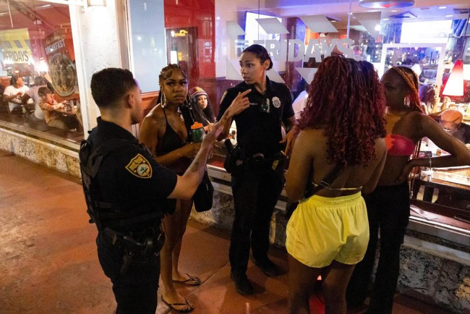 Miami Beach police officers talk to a group of women who were dancing near TGI Fridays off Ocean Drive during spring break on Friday, March 15, 2024, in Miami Beach. 