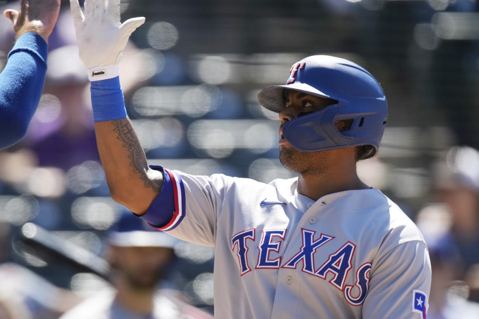 Texas Rangers' Khris Davis is congratulated as he crosses home plate after hitting a two-run home run off Colorado Rockies relief pitcher Jordan Sheffield in the seventh inning of a baseball game Thursday, June 3, 2021, in Denver. (AP Photo/David Zalubowski)