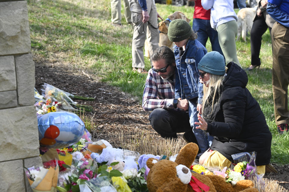 A family gathers to pay respects at an entry to Covenant School, Tuesday, March 28, 2023, in Nashville, Tenn., which has become a memorial to the victims of Monday's school shooting. (AP Photo/John Amis)