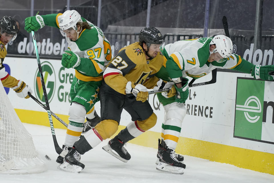 Minnesota Wild center Nico Sturm (7), Vegas Golden Knights defenseman Shea Theodore (27) and left wing Kirill Kaprizov (97) battle for the puck during the first period of an NHL hockey game Wednesday, March 3, 2021, in Las Vegas. (AP Photo/John Locher)