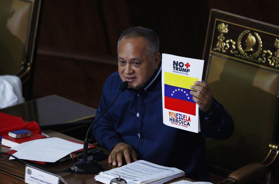 Venezuela's President of the National Constituent Assembly Diosdado Cabello holds up a sign that in Spanish says "No more Trump, heroic Venezuela" during a session by the legislative body that is stacked with government allies that rivals the opposition-controlled National Assembly in Caracas, Venezuela, Monday, Aug. 12, 2019. Legislators loyal to Venezuelan President Nicolás Maduro on Monday stripped immunity from four opposition lawmakers accused of treason amid a struggle for control of the crisis-stricken nation, bringing to 18 the number of opposition politicians Maduro's government has threatened with criminal prosecution this year. (AP Photo/Leonardo Fernandez)