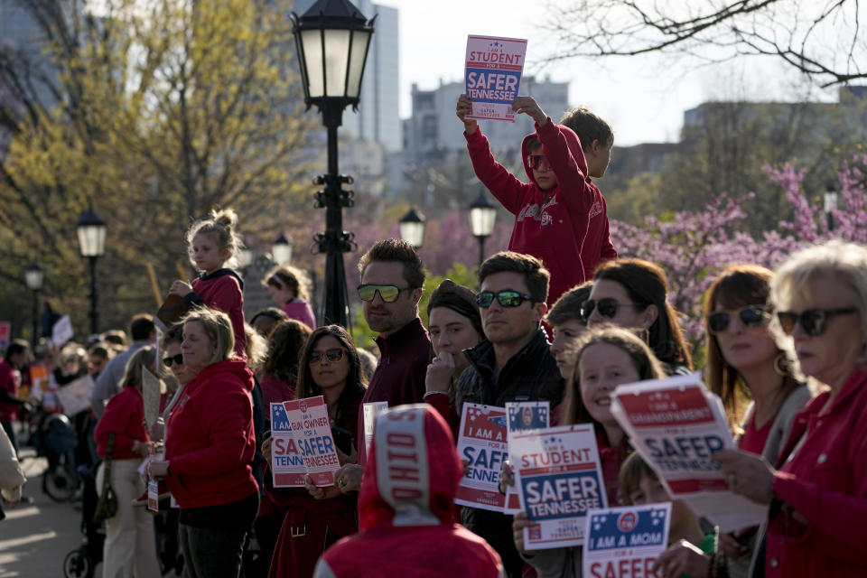 People hold signs along West End Ave. during the Linking Arms for Change human chain Wednesday, March 27, 2024, in Nashville, Tenn. The event was to commemorate the one-year anniversary of the Covenant School mass shooting. (AP Photo/George Walker IV)