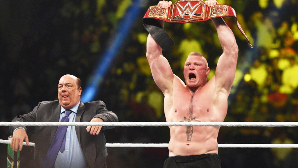 Brock Lesnar raises the belt and celebrates after winning the WWE Universal Championship match.