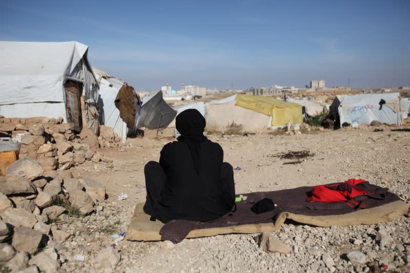 Woman sits in the sun on a cold winter day at a camp for internally displaced people in Khamir of the northwestern province of Amran