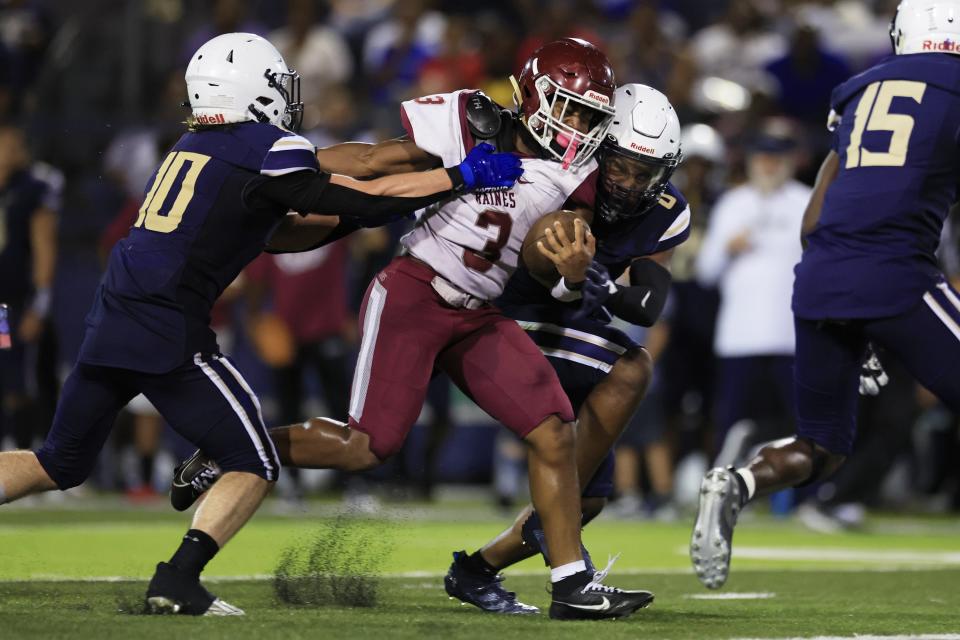 Raines' Mark Miller (3) rushes for yards against University Christian's Ayden Skidmore (10) and Dah'kari Gilley (0) during the second quarter.