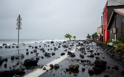 rocks swept by strong waves onto a road in Le Carbet, on the French Caribbean island of Martinique - Credit: LIONEL CHAMOISEAU/AFP