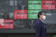 A man walks past an electronic stock board showing Japan's Nikkei 225 and other Asian indexes at a securities firm in Tokyo Monday, Oct. 26, 2020. Asian shares were little changed in muted trading Monday amid widespread uncertainty over what the U.S. presidential election will portend for markets and economic policy.(AP Photo/Eugene Hoshiko)