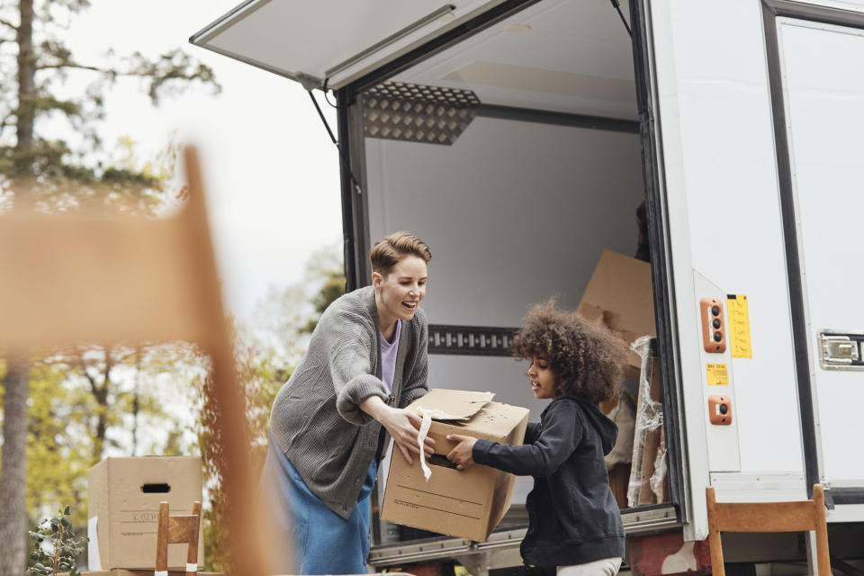 an adult and a little kid taking boxes out of a moving truck