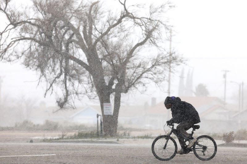 A person cycles through snow in Los Angeles County during another winter storm in Southern California on March 01, 2023 in Palmdale, California.