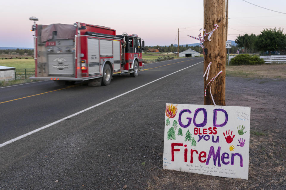 A firetruck responding to the Bootleg Fire is driven past a hand-painted sign thanking firefighters on Wednesday, July 21, 2021 in Bly, Ore. (AP Photo/Nathan Howard)