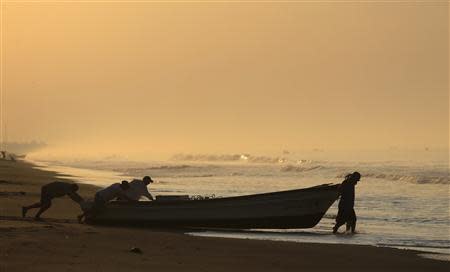 Fishermen push their boat into the sea in the fishing town of Ahuchapan, the hometown of castaway fisherman Jose Salvador Alvarenga, February 4, 2014. REUTERS/ Ulises Rodriguez