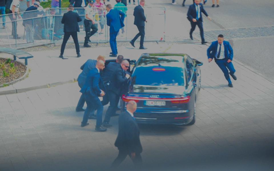 Security officers move Slovak PM Robert Fico in a car after he was injured in a shooting incident